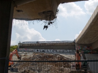 Die Reste des ersten Brückenabschnitts werden zusammengekehrt. Von oben hängen nur noch die Enden der Stahlseile herab.