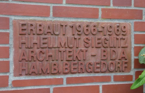 Ein Platte in der Fassade erinnert noch an den Architekten von 1966 - 1969,  H. Hellmut Sieglitz.