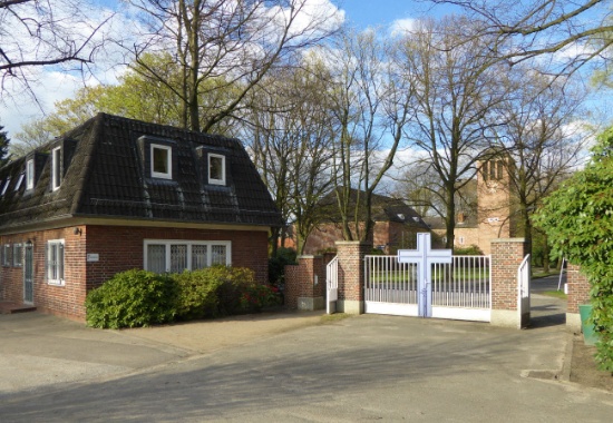 Haupteingang des Stellinger Friedhofs von innen, links das ehemalige Gebäude der Verwaltung und vor dem Friedhofstor die Stellinger Kirche.