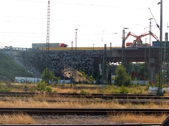 Die seitlichen Teile der Fahrbahn hängen neben dem Hohlkasten an Stahlseilen Stückweise herunter.